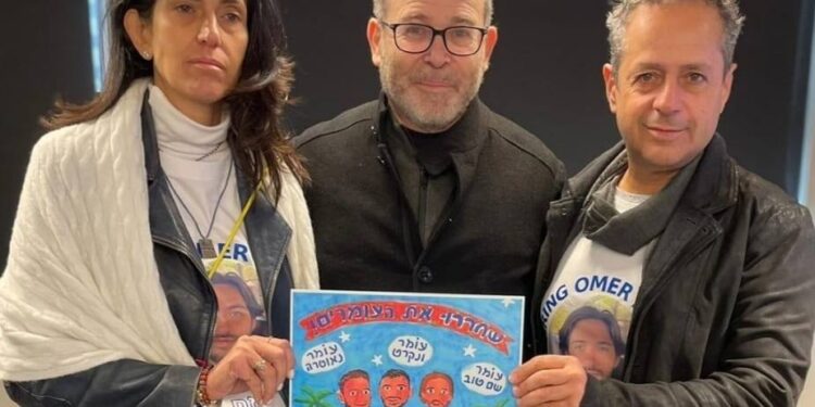 האמן זאב אנגלמאיר, מעניק את הגלויה היומית להוריו של עומר שם טוב. צילום מתוך עמוד הפייסבוק של האמן