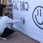 עומר לקח ספריי צבע וריסס על יריעת הבד סמיילי מחייך ואת המשפט המרגש: "כמה טוב להיות". צילום דוברות העירייה