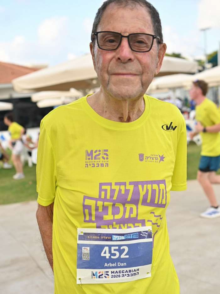 תושב הרצליה דן ארבל, בן 89, מחויך ומתרגש, מצולם בתקריב עם חולצת המרוץ הצהובה ומספר החזה 452, רגע לפני הזינוק במרוץ הלילה. צילום: דוברות העירייה