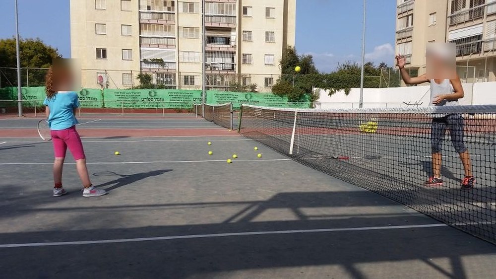 שיעור טניס במגרשי הקאנטרי, ברקע בניני המגורים הגובלים בשטח. | קרדיט: פרטי