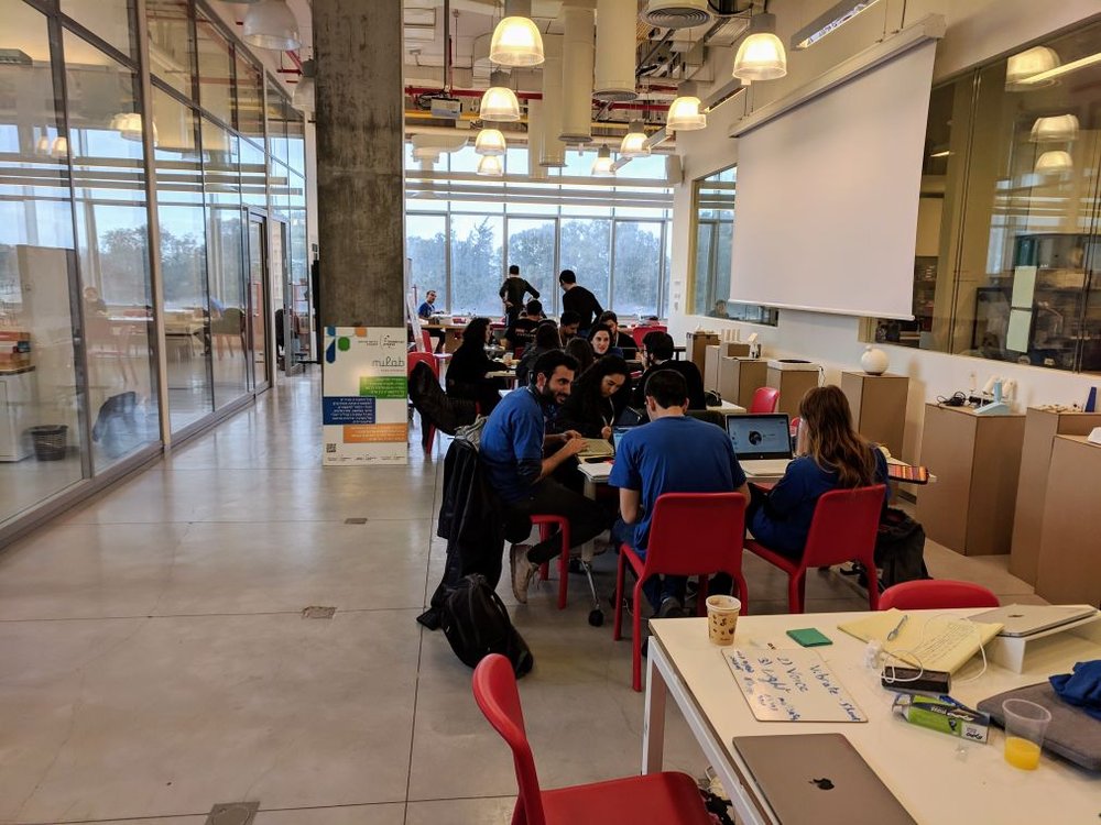 סטודנטים יושבים סביב שולחן משותף במרחב שיתופי בקמפוס אוניברסיטת רייכמן