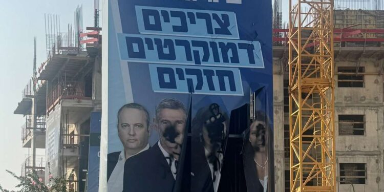 שלט חוצות של הדמוקרטים עם קרעים וכתמי צבע שחור בפינת ירושלים והבריגדה בהרצליה.